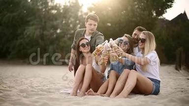 一群朋友在<strong>日</strong>落时分在海滩上玩着享受饮料和放松的乐趣。 男女<strong>青年</strong>